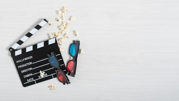 Mozi clapperboard, színes 3D-s szemüveg és popcorn fehér fa háttér felülnézet. Mozi háttér. - Fotó, kép