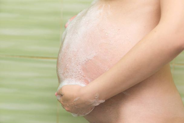 embarazada chica lava su vientre en la ducha. - Foto, Imagen