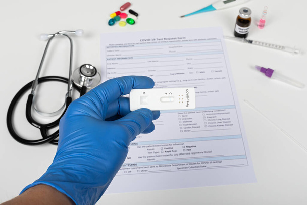 Close up picture of doctors hand holding coronavirus test and medical paperwork on white background - Valokuva, kuva