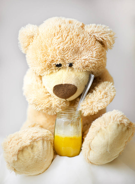 De teddybeer zit honing te eten. - Foto, afbeelding