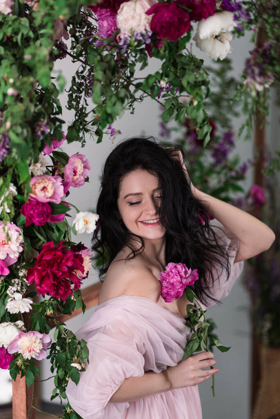 Indoor studio shot van zoete schattige jonge vrouw met witte, roze en paarse bloemen in handen. - Foto, afbeelding