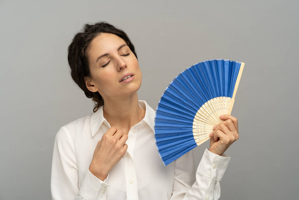Stanco dipendente donna surriscaldata sbottona pulsante superiore della camicetta, utilizzando ventilatore onda soffrono di sudorazione di calore - Foto, immagini