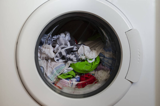 Waschmaschinentür mit rotierenden Kleidungsstücken innen - Foto, Bild