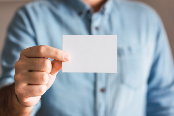 Boş kağıt kartvizit modeli, bir adamın elinde, yakın plan. Logo ve marka tasarım şablonu kavramı - Fotoğraf, Görsel