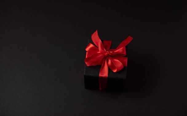 Top view of black gift boxes with red ribbon on black background with copy space for text. The Concept Of Valentine's Day. - Фото, изображение
