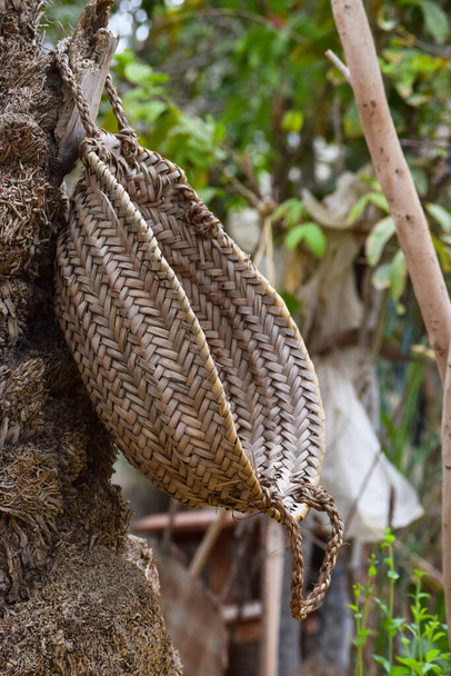 Handgemachtes Kastenwerkzeug mit Dattelbaumblatt, handtellertrockenes Glas, das auf Holz im Garten hängt, brauner Hintergrund Kultur Sache Tapete - Foto, Bild
