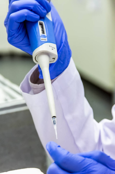 Naukowiec umieszczający próbkę w probówce podczas noszenia rękawic ochronnych - Zdjęcie, obraz