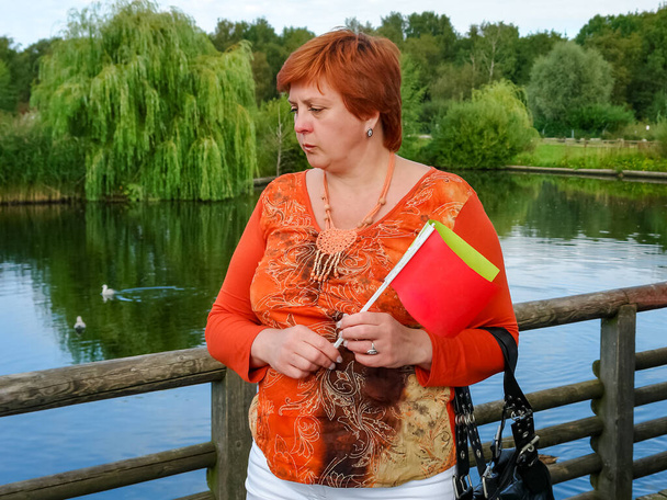 Fröhliche reife Frau ruht sich im Stadtpark am See aus - Foto, Bild