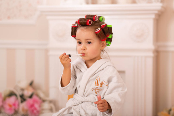 Adorable little girl with her mother in hair curlers apply makeup. Mom teaches daughter to use cosmetics. Beauty day. Girls are such girls. - Фото, изображение