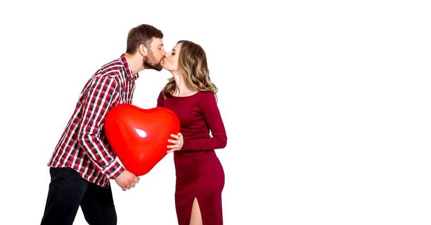 Muž a žena políbí na bílém pozadí a drží v rukou velkou nafukovací červenou kouli ve tvaru srdce. Koncept svátku - Valentýn, Mezinárodní den žen, Den matek. - Fotografie, Obrázek