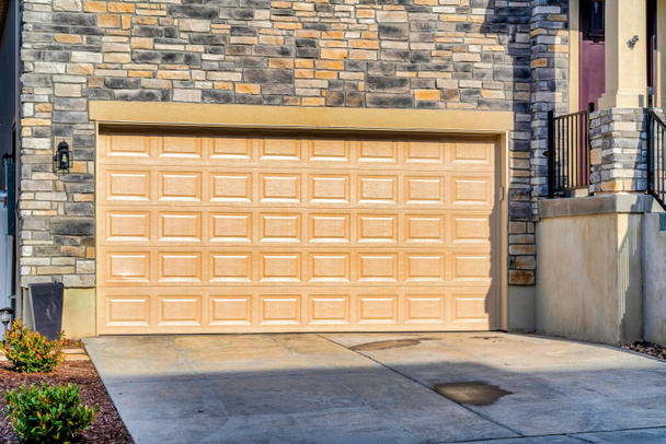 Široká obložená garážová vrata domů s kamennou cihlovou zdí na slunné čtvrti - Fotografie, Obrázek