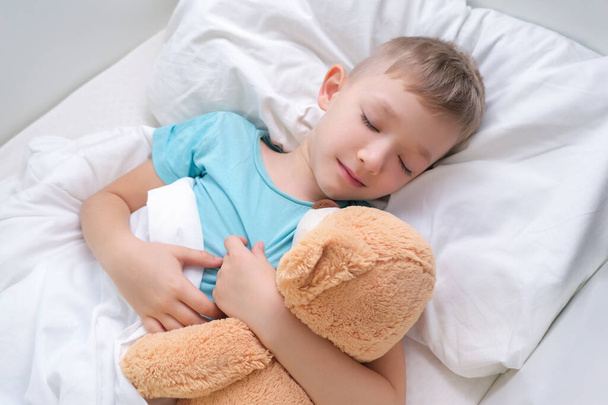 boy sleeping sweetly hugging a toy bear - 写真・画像
