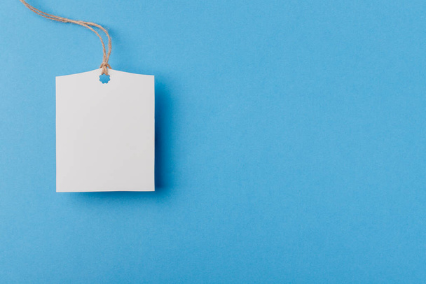 mockup empty white rectangular paper tag on a rope on blue background - 写真・画像