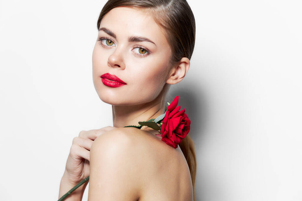 Mujer joven Labios rojos rosa flor en los hombros mirada atractiva  - Foto, imagen
