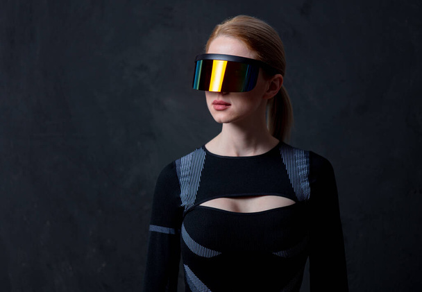 Ξανθιά γυναίκα ανδροειδές σε γυαλιά VR και κοστούμι σε σκούρο φόντο. - Φωτογραφία, εικόνα