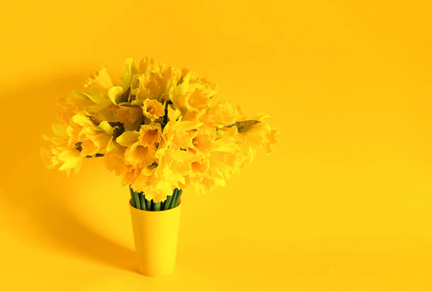 Beautiful bouquet of spring yellow narcissus flowers or daffodils on bright yellow background. - Foto, imagen