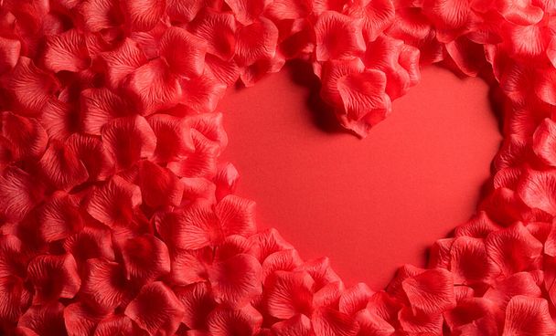 Liefde en Valentijnsdag concept. Rode harten gemaakt van rozenblaadjes op rood papieren achtergrond. Platte lay bovenaanzicht. - Foto, afbeelding