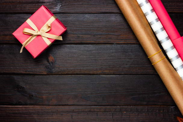 Pink gift and wrapping paper on a dark wooden background. View from above. - Foto, Imagem