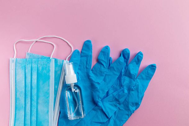 Medicine mask, protective gloves and antibacterial gel on pink background. Pandemic of coronavirus. - Photo, Image