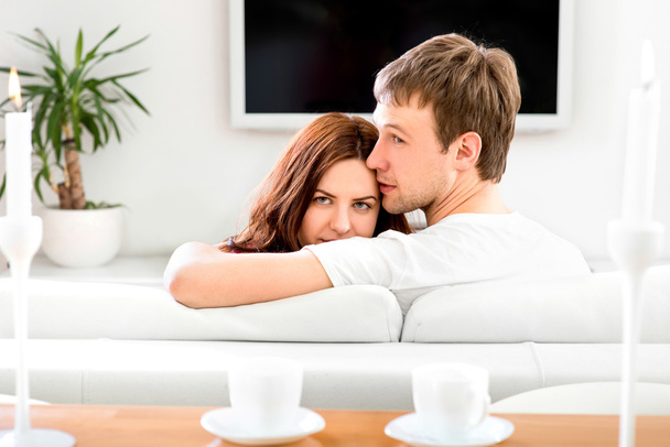 Молода подружня пара сидить на дивані і дивиться телевізор вдома
 - Фото, зображення