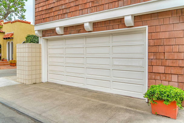 Weiße Tür von zwei Autogaragen des Hauses mit Schindelverkleidung an der Außenwand - Foto, Bild