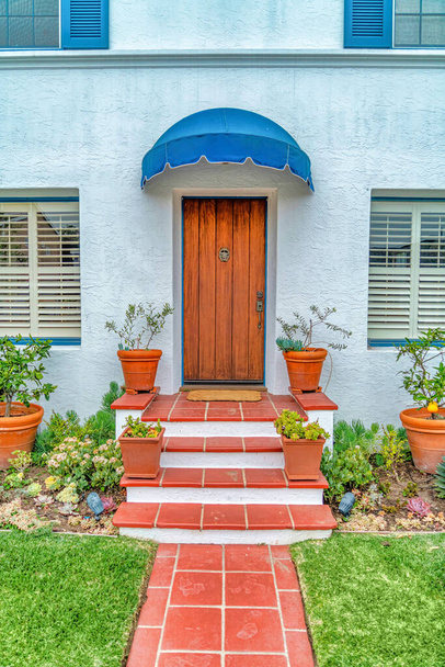 Дом с красной тропинкой и лестницами, ведущими к коричневой деревянной входной двери - Фото, изображение