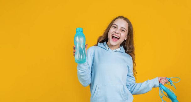 happy smiling child girl hold sport or fitness equipment of jumping rope and water bottle, health - Foto, immagini