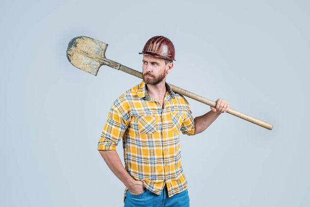 Confident worker. mature builder in shirt. unshaven man on construction site. handsome building worker in hard hat. labor day. guy wear safety helmet hold shovel. engineer on work. male lifestyle - Photo, image