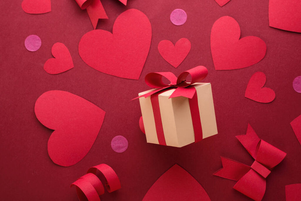 Happy st. Valentinstag Konzept mit Bastelpapier Geschenkschachtel, rote Papierherzen, Bögen vor dunkelrotem Hintergrund mit Platz für Text. - Foto, Bild