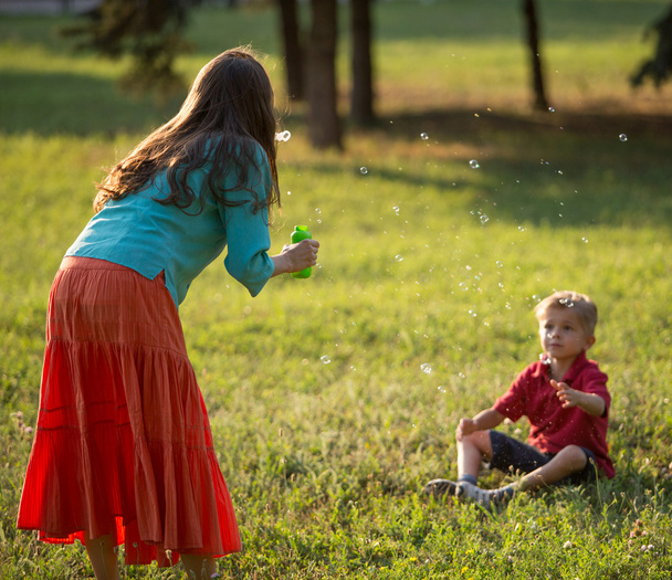 Happy family blowing bubbles in the park - Photo, Image