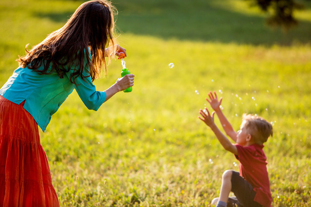 Happy family blowing bubbles in the park - Foto, Imagem