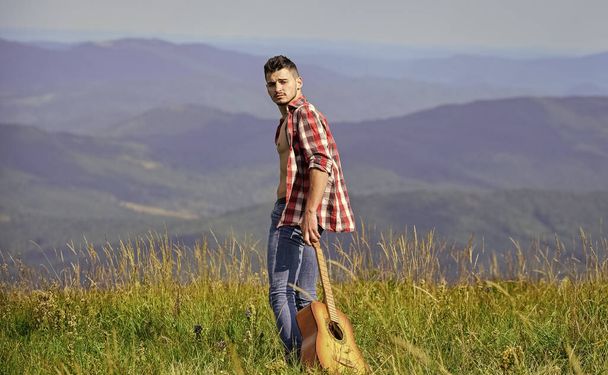 Looking for inspiration. Fresh mountain air. Exploring nature. Beauty of nature. Walking alone. Man with guitar walking on top of mountain. Vacation destinations. Guy hiker enjoy pure nature - Foto, afbeelding