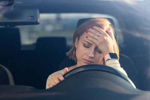 Przygnębiona kobieta, siedząca w samochodzie, wypalona emocjonalnie po pracy. Przewlekłe zmęczenie   - Zdjęcie, obraz
