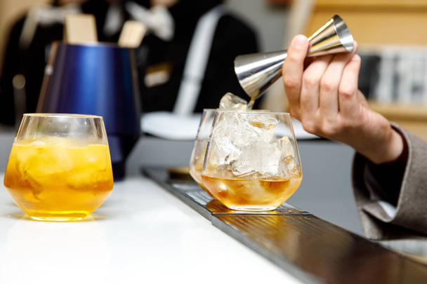 Il barista prepara un cocktail. I barman versano alcool da un bicchiere di acciaio - Foto, immagini