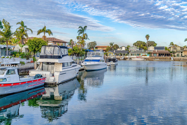 Yachts on rauhallinen vesi, joka heijastaa pilvinen sininen taivas Huntington Beach CA - Valokuva, kuva