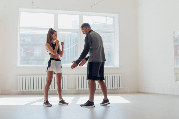 A young attractive boxing coach prepares a pretty girl for competition - Photo, Image