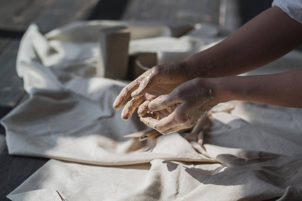 Womans hands wet and dirty after working with clay in a pottery studio - Foto, immagini