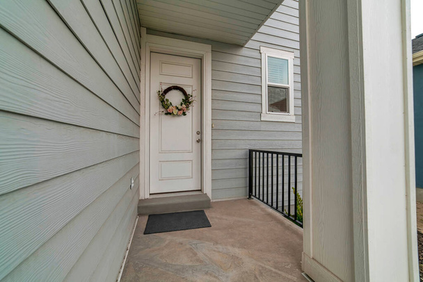 Fedett ház verandával és fehér fa bejárati ajtóval koszorúval díszített - Fotó, kép
