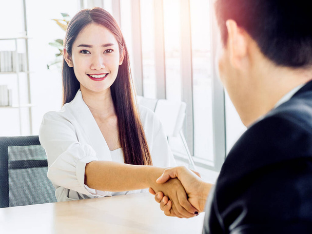 Young smiling happy woman candidate handshake with businessman in suit, employer after job interview. Business people shaking hands at meeting in office. Success teamwork, partnership and handshake. - Photo, Image