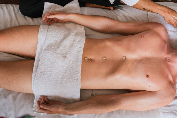 Zdjęcie nierozpoznanego mężczyzny korzystającego z masażu ciała leżącego na podłodze. - Zdjęcie, obraz