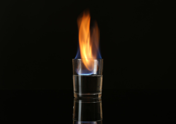 Glass with burning alcohol on black background - Photo, Image