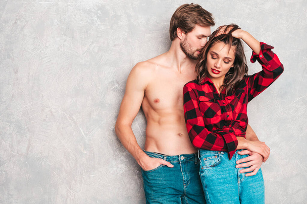Hot beautiful woman and her handsome boyfriend. Models posing near gray wall in jeans clothes. Young passionate couple hugging before having sex. Sensual pair getting closer for kiss. Lover couple - Photo, Image