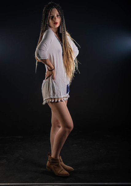 Attractive female feminist waring tribal short white dress. The isolated photo on a black background. Woman queen concept. - Photo, Image