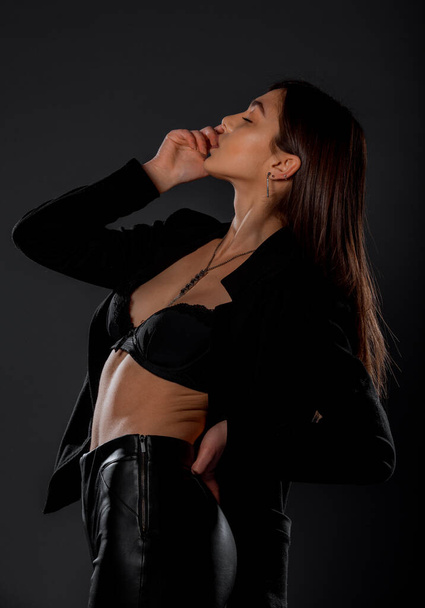 Portrait of a beautiful stylish woman posing against black background - Photo, Image
