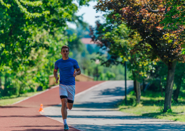 Bell'uomo che fa jogging durante la soleggiata mattinata in pista - Foto, immagini
