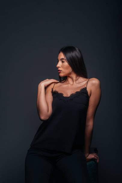 Beautiful sexy woman with straight black hair looking aside and being isolated on a dark background - Photo, Image