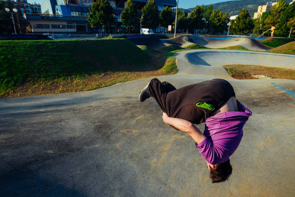 Junger Mann in der Mittagspause beim Rückwärtssalto im Skatepark - Foto, Bild