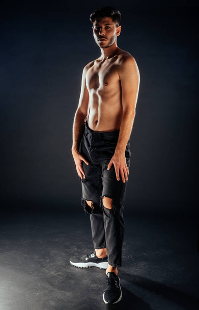 Stijlvolle fashion guy poseren topless tegen donkere achtergrond - Foto, afbeelding