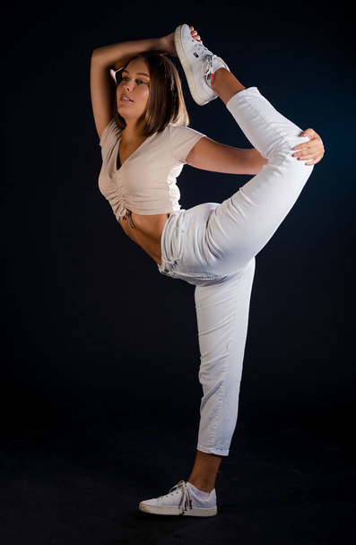 Energetische Tanzhallentänzerin springt mit erhobenem Bein in mittlerer Luftposition - Foto, Bild