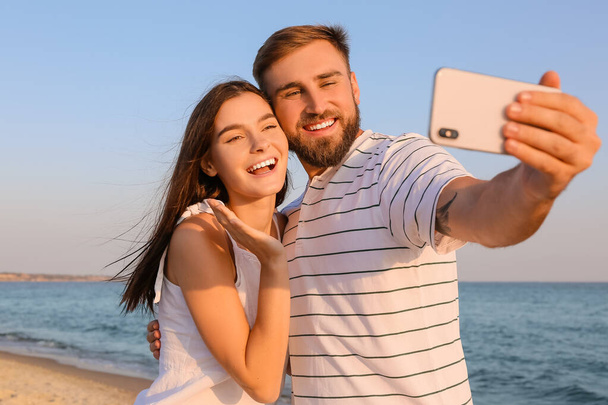 Boldog fiatal pár szelfizik a tengerparton - Fotó, kép